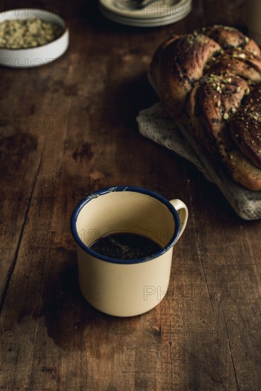 Top view of a freshly baked Bakbah bread garnished with pistachio, alongside a vintage tin cup