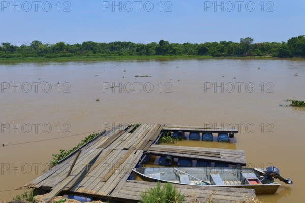 A wooden jetty on the riverbank with a boat tied just below the water surface, Porto Jofre,