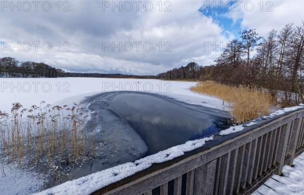 View of the church lake covered with ice and snow on the bridge tour, a hiking trail with a wooden