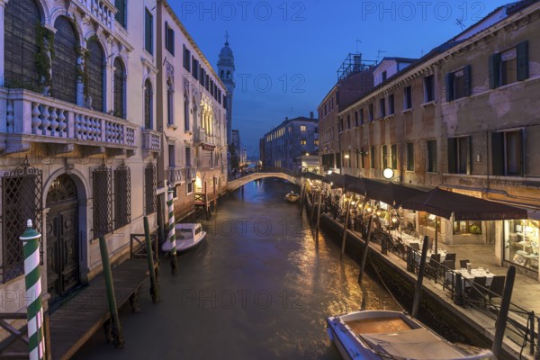 Dinner with restaurant on the canal, in the back the tower of the church of Santa Maria della