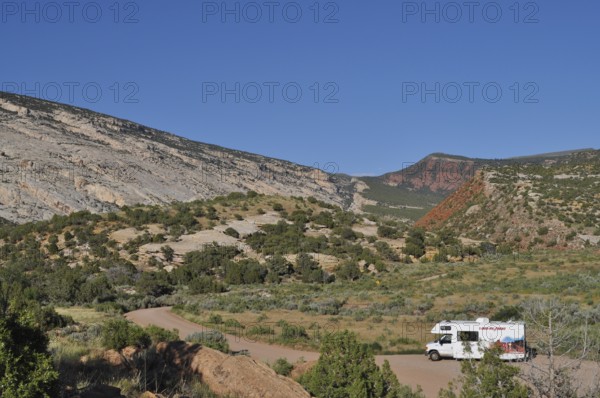 An RV parks in a picturesque mountain landscape with clear skies, Dinosaur National Monument, Utah,