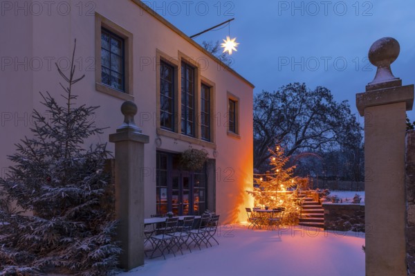 Illuminated Christmas tree and Herrnhut star in the snow at the Aust winery in Radebeul, Saxony,