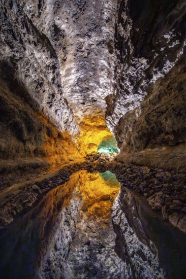 Lava tunnel, illuminated lava cave with perfect reflection in an underground lake, Cueva de los