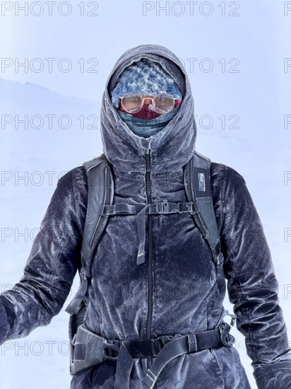 Young woman wearing thick winter clothes, down jacket and scarf, with frozen snow in cold weather,