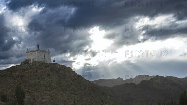 Small monastery on a mountain under dramatic cloudy sky, Leh, trekking in Ladakh, Stok la,