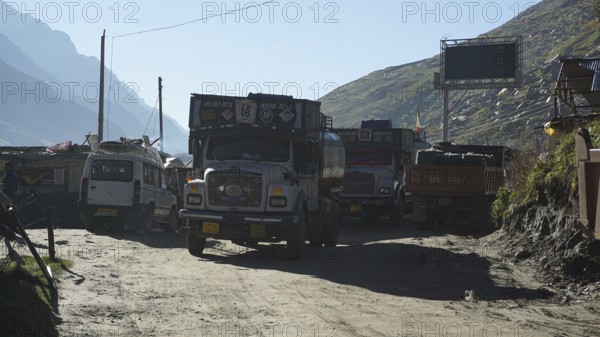 Several trucks on a mountain road in a small village in sunny weather on the Manali-Leh Highway,