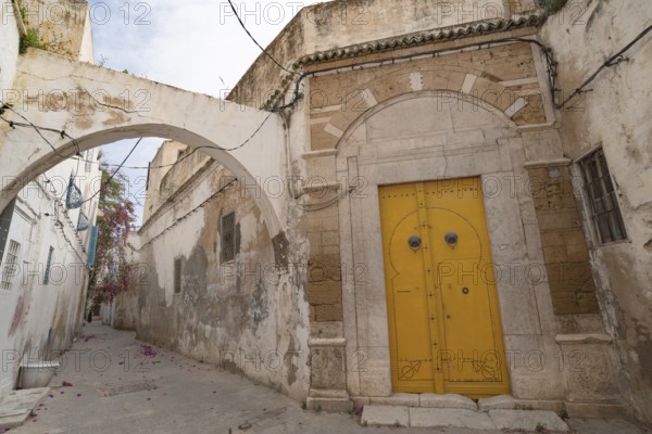 An ornate yellow door of typical Tunisian architecture in the colourful alleyways of the Medina in
