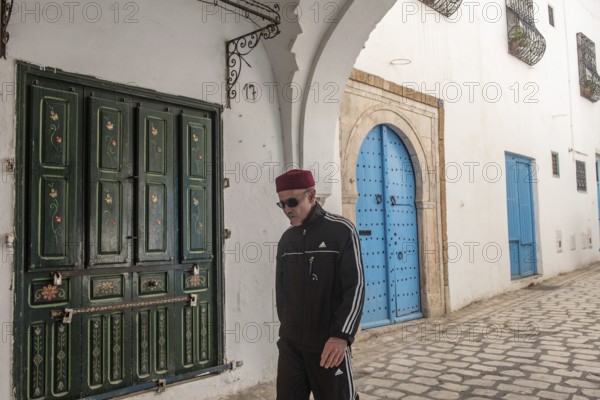 Tunis, Tunisia 4th May, 2024 A Tunisian man wearing a red chechia hat in the beautiful narrow