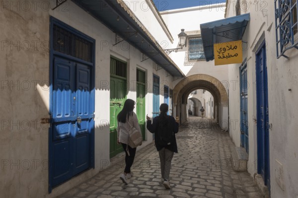 Tunis, Tunisia 4th May, 2024 Two young Tunisian women walk in the traditionally decorated narrow