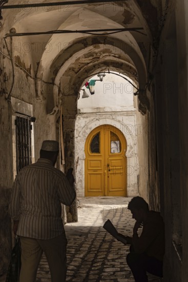 Tunis, Tunisia. 13th May 2024 A dark narrow alley with a bright yellow door, a traditional scene in