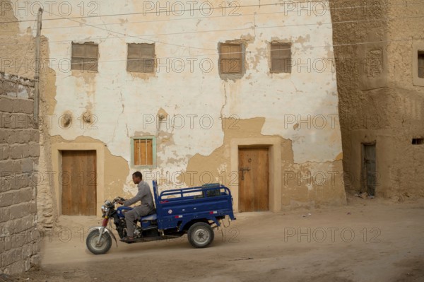 Siwa, Egypt, April 11th 2018 Motorcycle pick-up being driven through the mud brick houses of Siwa