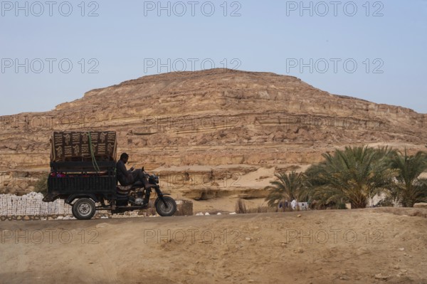 Siwa, Egypt. March 11th 2018 A tuc tuc driver checks his phone while parked in the desert of Siwa