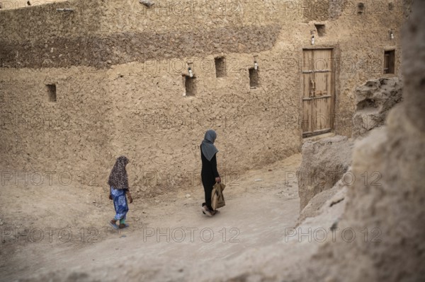 Siwa, Egypt. March 11th 2018 A woman and child walk through the traditional mud brick buildings of
