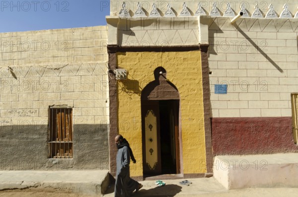 Aswan Egypt. January 10th 2013 Nubian Muslim man leaving a brightly coloured Mosque on Elephantine