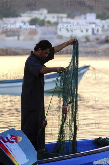 Tiwi, Oman. May 26th 2014. Silhouette of Omani fishermen at sunset in the fishing village of Tiwi