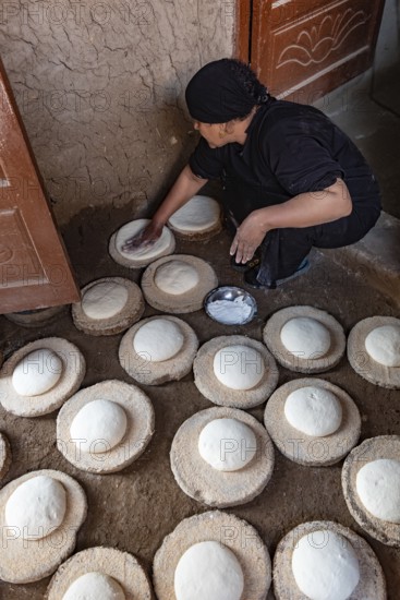 Luxor, Egypt. 13th December 2020 An Egyptian woman preparing dough to make bread in a Nile side