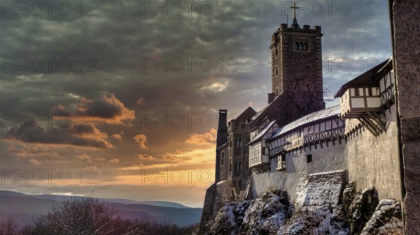 Snowy Wartburg in Eisenach in front of a picturesque and dramatic sky in romantic colors, at dusk,