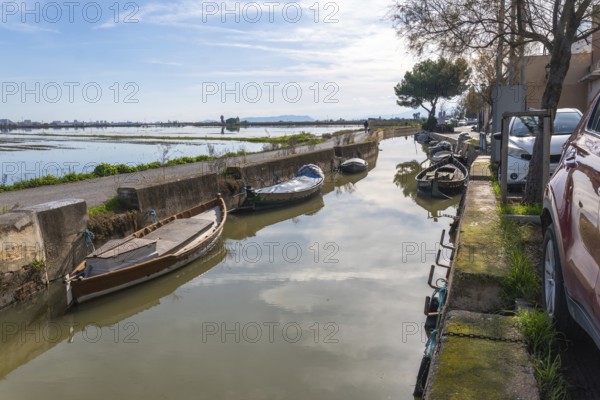 Traditional boats moored along a narrow canal in el palmar fishing village, reflecting the sky and
