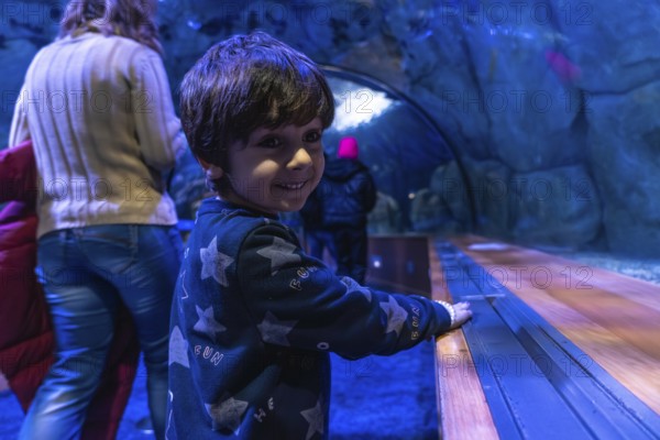 Young child with dark hair smiles, looking over shoulder while enjoying an immersive visit to an