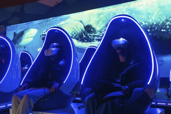 People wearing virtual reality headsets enjoying an immersive deep sea experience while sitting in