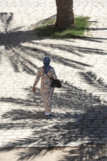 A Tunisian muslim wearing a patterned dress women walks in the streets of Sfax, the second largest