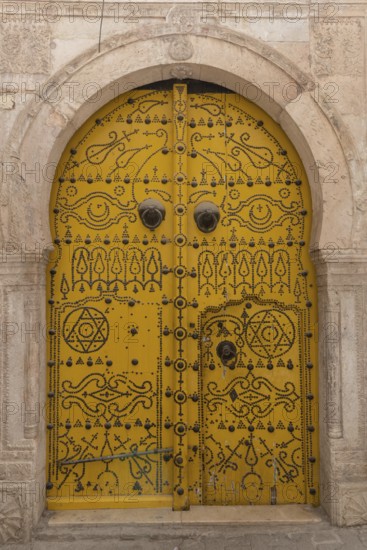 Detailed yellow ornate design of a typical door in the Medina of Tunis, a UNESCO designated quarter