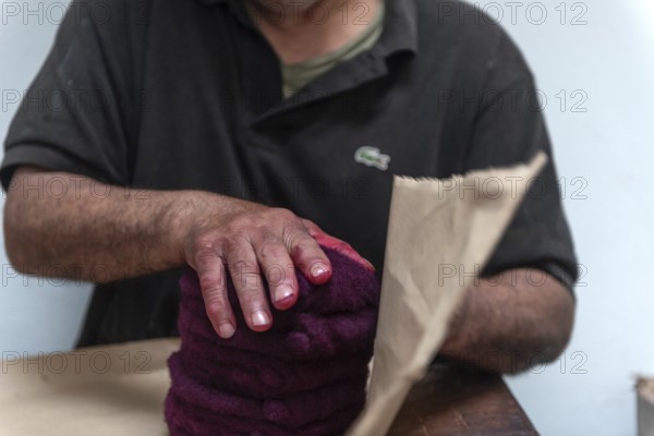 Tunis, Tunisia 22nd May, 2024 A Tunisian Chaouachis works with a vermillion red dye in the making