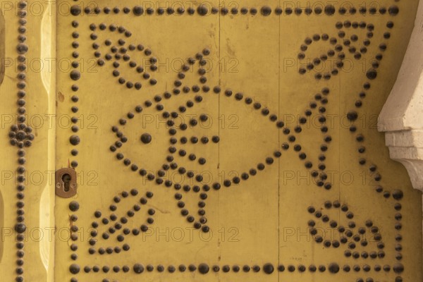 Distinctive fish design, an architectural detail of a traditional yellow painted door in the Medina