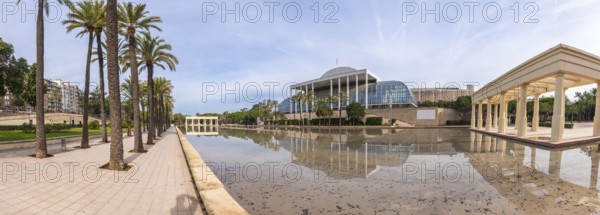 Palau de la musica concert hall architecture reflecting in a calm water pond, surrounded by palm