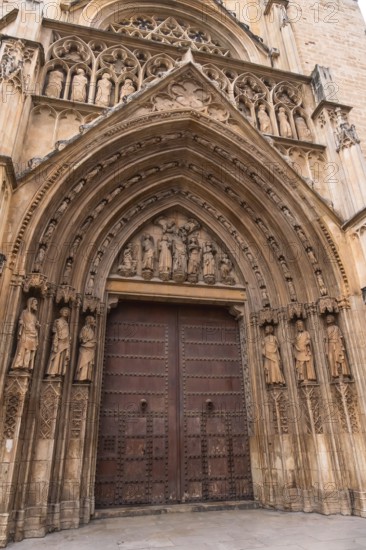 Valencia cathedral's door of the apostles displaying intricate gothic stone carvings. Religious