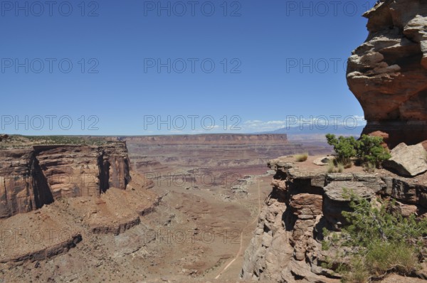Rock cliffs with spectacular views of the vast, dry desert landscape and a narrow gravel road,