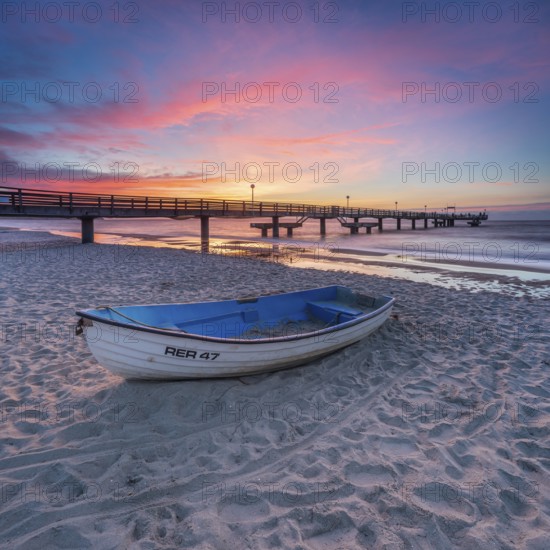 Pier on the fine sandy beach of the Baltic Sea at sunset, fishing boat on the beach, Baltic resort