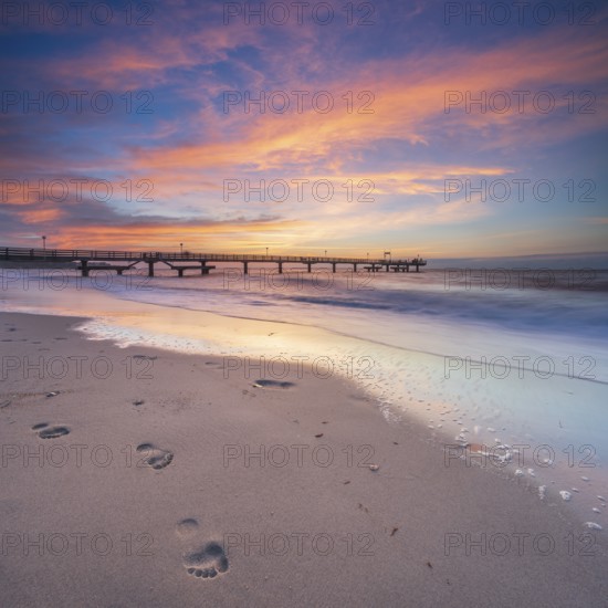 Pier on the fine sandy beach of the Baltic Sea at sunset, footprints in the sand, Baltic resort