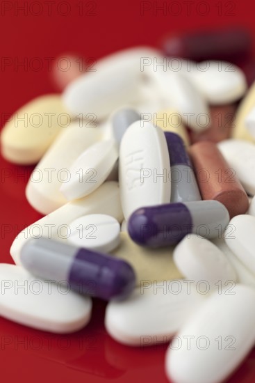 A close-up image showcasing a variety of medical pills and capsules in white, purple, and red