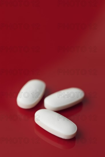 A minimalist image featuring three oblong white tablets, subtly embossed, isolated against a deep