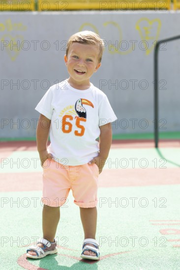 Cheerful young boy with hands in pockets smiling brightly on a sunny day He wears a casual outfit,