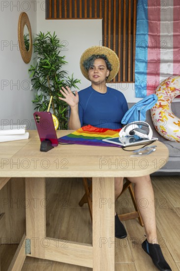 Transgender man hosting a virtual meeting from home, displayed on a smartphone. He is gesturing