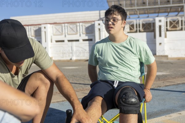A teenager with Down Syndrome has knee pads adjusted by a family member, preparing for