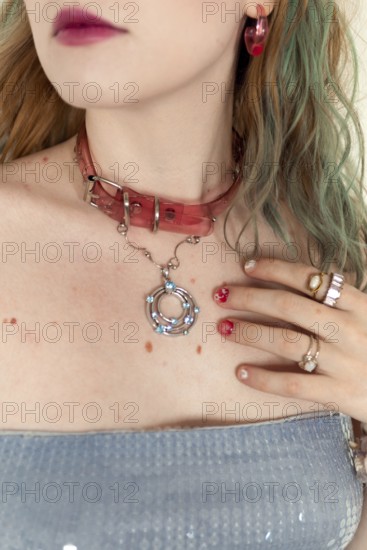 A stylish woman with a pink choker, rings, and earrings Her colorful hair complements the artistic