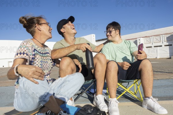 Down syndrome teenager sits with family members, sharing laughter and joy during an outdoor sports
