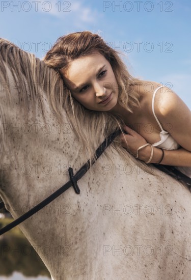A serene scene of a young woman gently resting her head against a horse, conveying a deep