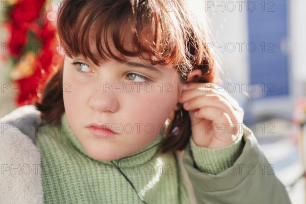 Close-up of a young girl adjusting her headphones, highlighting a thoughtful expression with a soft
