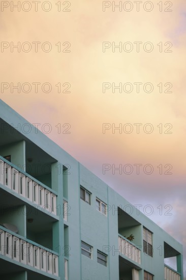 Soft sunset colors bathe a Miami Beach building, rendering the sky in warm peach tones above the