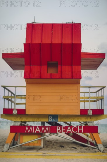Vibrant red and orange lifeguard stand prominently positioned on Miami Beach, captured during a