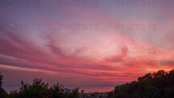 Captivating view of a vivid sunset painting the skies in shades of pink and red, over Lausanne and