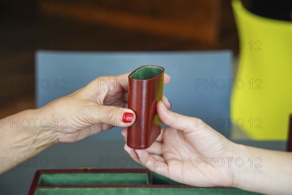 Two hands exchange a brown dice cup during a backgammon game, showcasing a moment of strategy and