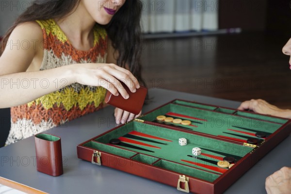 A woman engaging in a strategic game of backgammon, rolling the dice in anticipation A green and