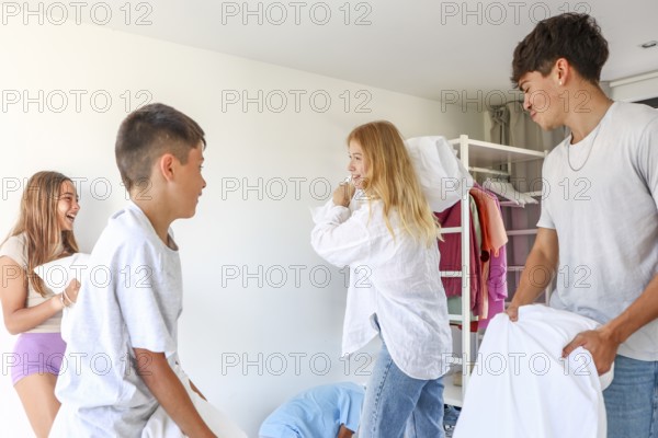 Young siblings enjoy a playful pillow fight in a bright bedroom. The image captures three triplets,