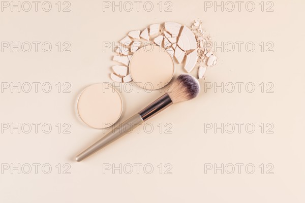 Top view of a styled makeup layout featuring compact powder in whole and broken forms, and loose
