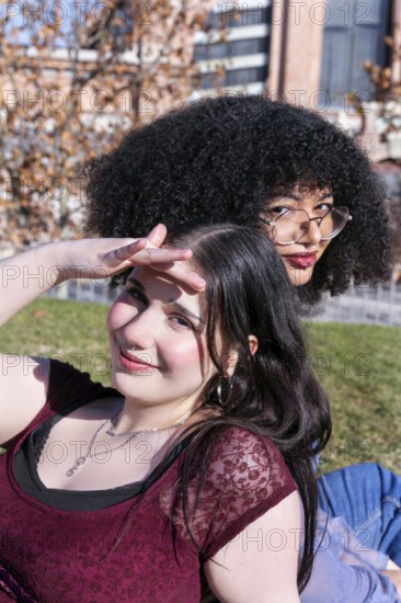 Two Gen Z friends, one Hispanic girl with curly hair and another girl with straight black hair,